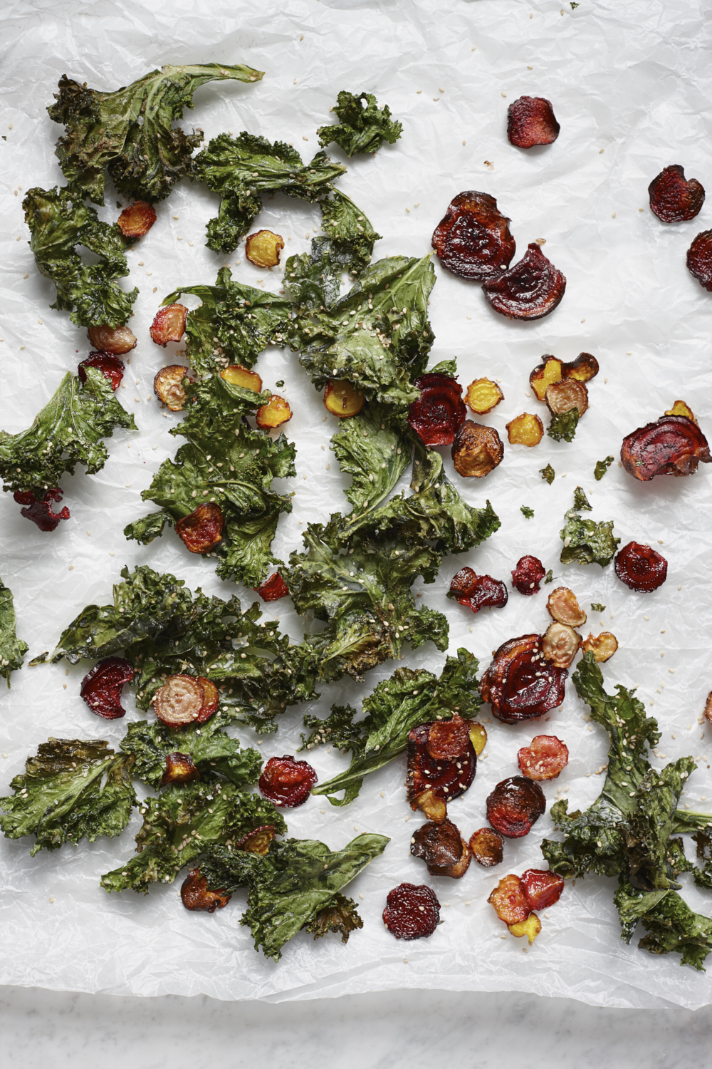 Oven roasted beetroot and kale crisps on white baking parchment. Food photography by Joanna Henderson
