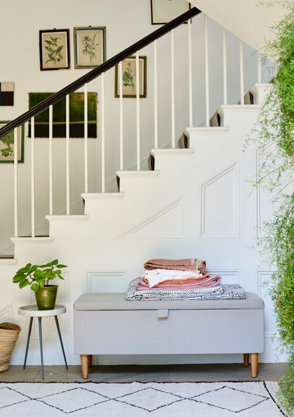 Blanket box with white staircase, blush pink blankets and greenery. Still life photography by Joanna Henderson