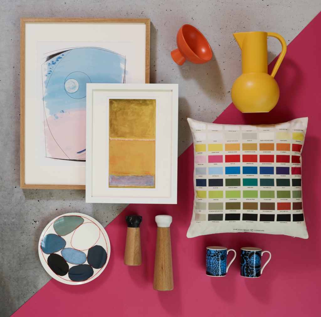 Framed prints, ceramics, salt and pepper pots and multi coloured cushion on a bright pink background